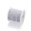 A spool of gray stretchy rainbow elastic cord used for jewelry making.