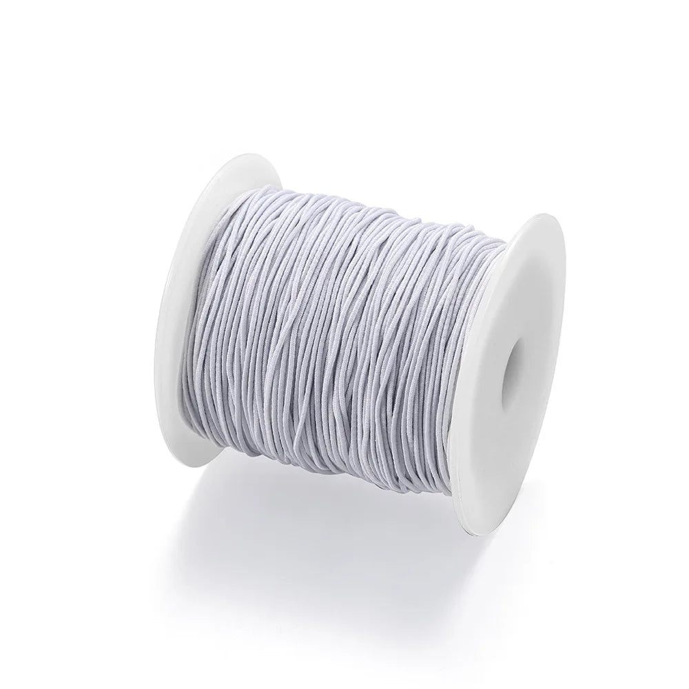 A spool of gray stretchy rainbow elastic cord used for jewelry making.