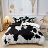 A black and white cow print duvet cover set with matching pillowcases displayed on a bed.