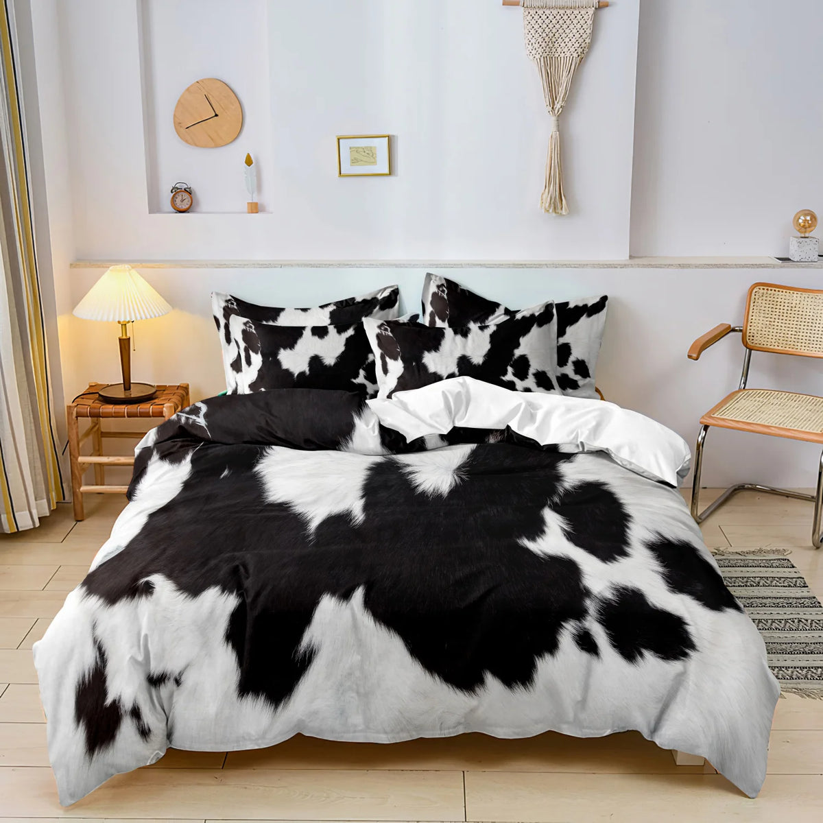 A black and white cow print duvet cover set with matching pillowcases displayed on a bed.