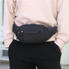 A black canvas waist pack with zippers is shown being held by a person wearing a light pink top and black pants.