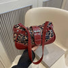 A close-up of a red leather leopard print shoulder bag being held against a light background.
