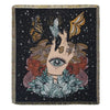 A dark woven blanket featuring a stylized hand with an eye surrounded by floral and feather motifs against a starry backgroun