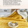 A yellow fleece throw blanket is draped over a bed, with a white fleece blanket folded beside it.