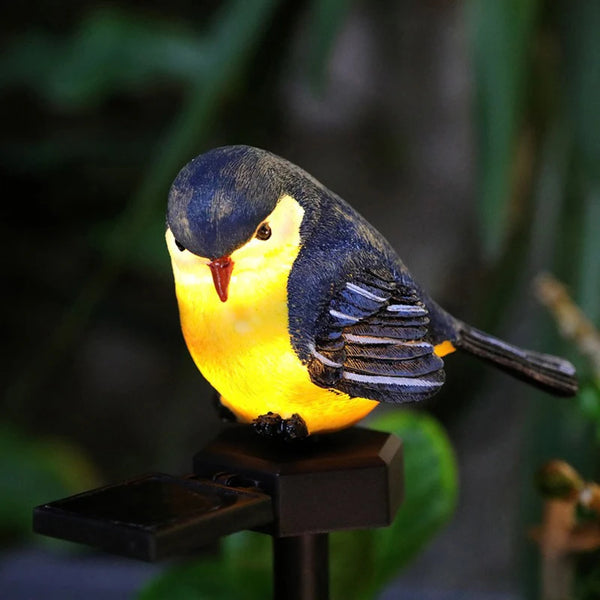 A small, yellow and black bird figurine mounted on a dark stake for a solar-powered garden light.