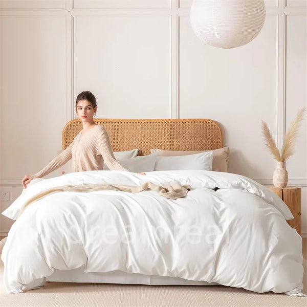 A woman is posing in a bright bedroom with a light wood headboard and white bedding.