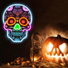 A glowing neon skull light featuring vibrant colors and an carved pumpkin in a dark, spooky setting.