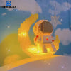 A luminous building block set shaped like an astronaut and a crescent moon, illuminated with warm yellow light.