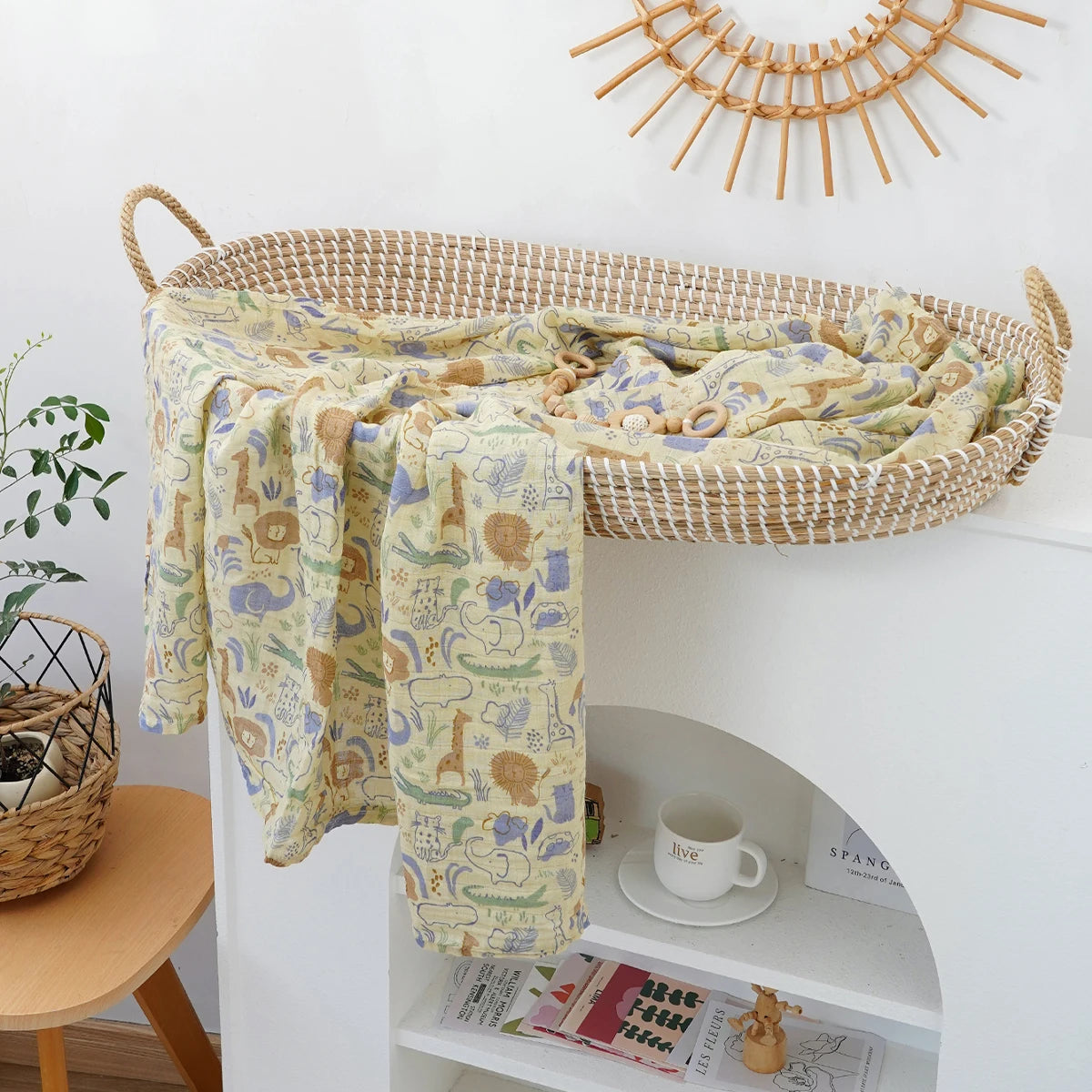 A woven basket holds a patterned muslin baby swaddle blanket draped over the edge of a white shelf.