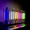 A row of glass tubes displaying various colors of warm filament glow lights on a dark surface.