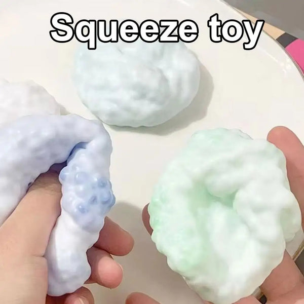 Une main serre une balle en peluche blanche et vert clair.