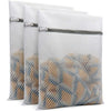 A set of three clear mesh laundry bags filled with delicates and stored in a gray fabric pouch.