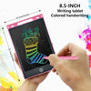 A hand holds an 8.5-inch pink LCD writing tablet displaying colorful handwriting on a black screen.