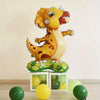 A yellow dinosaur foil balloon standing on a green leaf base with several loose green and yellow balloons.