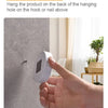A hand is placing a white motion sensor LED night light onto a wall, demonstrating the hanging installation method.