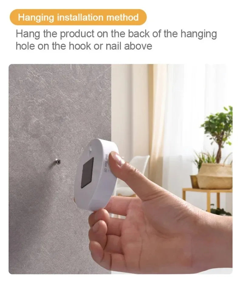 A hand is placing a white motion sensor LED night light onto a wall, demonstrating the hanging installation method.