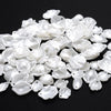 A pile of 100 clear and white acrylic pearl spacer beads for jewelry making.
