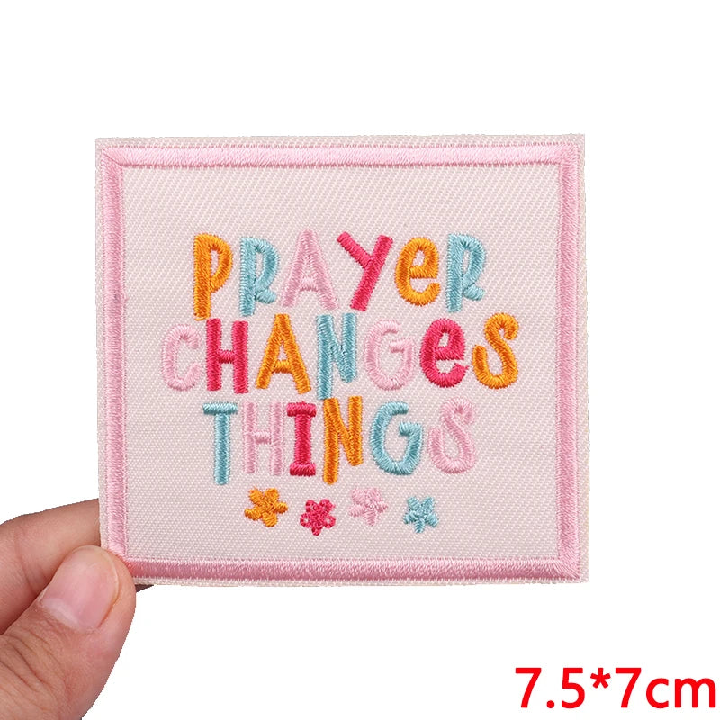 Pink embroidered patch with colorful letters spelling out PRAYER CHANGES THINGS