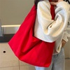 A person holds a bright red lightweight nylon tote bag against their chest.