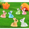 A set of cute resin miniature bunny figurines in various pastel colors sitting on green grass.