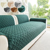 A dark green quilted anti-slip sofa cushion is displayed on a white sofa with light beige fabric.