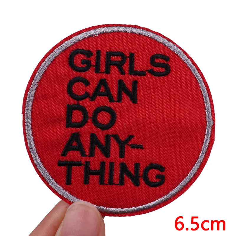 Red embroidered patch with black text that reads Girls can do anything