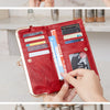 A close-up of a vintage red leather wallet with gold accents and various cards being held by hands.