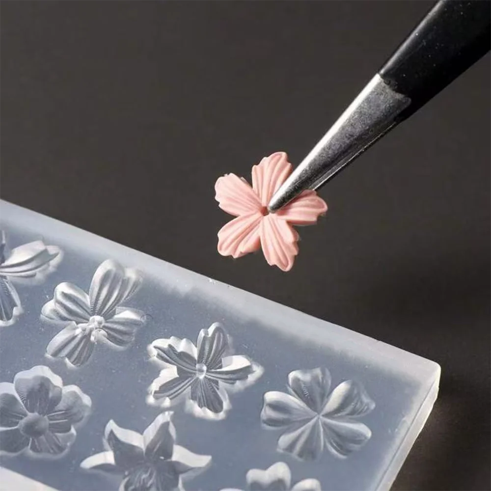 A fine black tool is applying a pink 3D lily flower detail onto a clear silicone nail art mold.