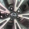 Close-up view of a Nissan wheel with four silver spoke hub caps.