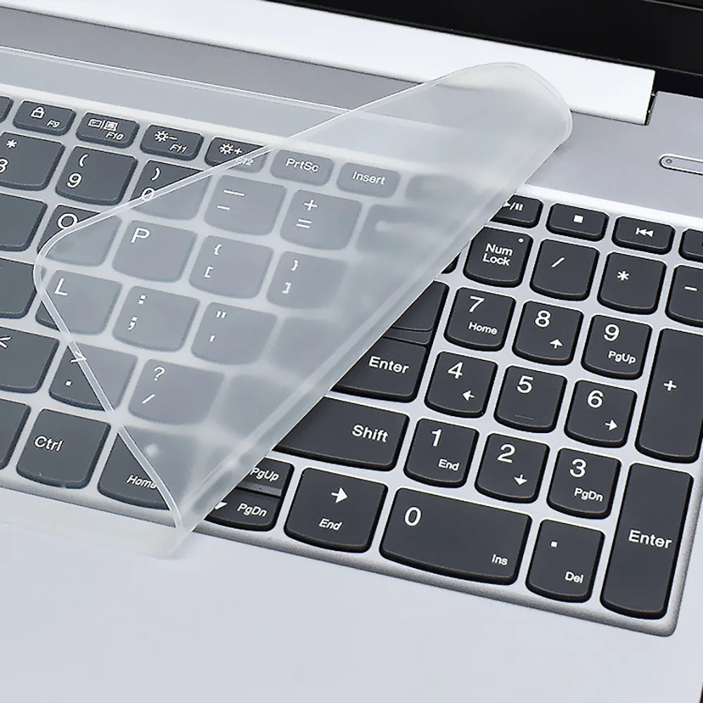 A clear silicone keyboard cover is placed on a silver laptop keyboard.