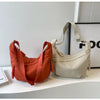 A light beige nylon crossbody bag with adjustable straps resting on a white surface.