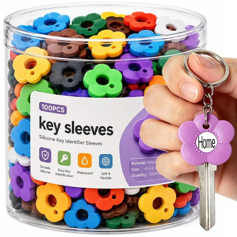 A hand holds a clear container filled with colorful silicone flower key sleeves for easy key identification