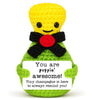 Handmade crochet yellow animal doll with a black bow and a green body, featuring a positive message card.