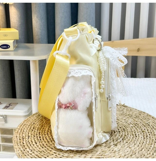 A yellow transparent shoulder bag with white fur trim and lace detailing resting on a woven mat.