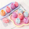A collection of pink and purple 3D tulip silicone molds for candle and soap making displayed on a white surface.