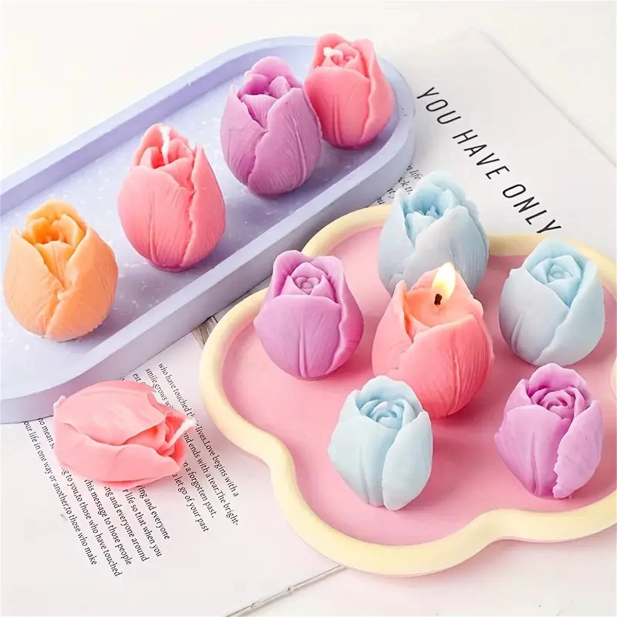 A collection of pink and purple 3D tulip silicone molds for candle and soap making displayed on a white surface.