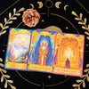 Tarot oracle deck featuring three cards with celestial imagery and a pinecone on a dark background