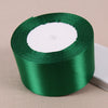 A roll of emerald green lustrous satin ribbon with a white center core.