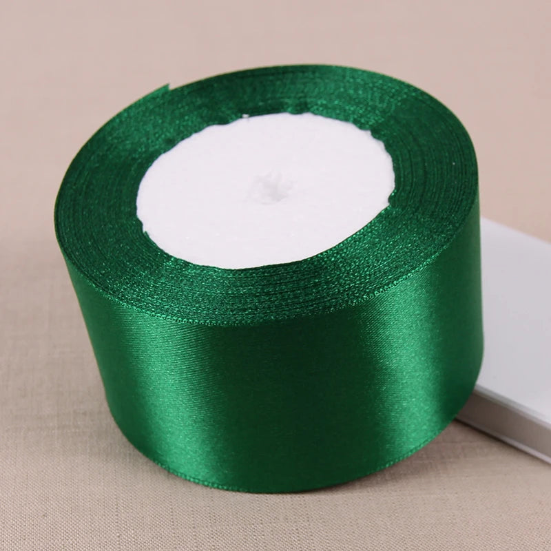 A roll of emerald green lustrous satin ribbon with a white center core.