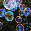 Colorful soap bubbles floating in the air against a dark green background.