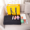 A yellow tote bag with black straps is displayed on a light gray sofa next to various personal items.