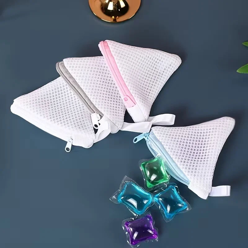 Three reusable white mesh laundry bags with pink accents and colorful fabric pouches are displayed on a dark surface.