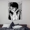 A black and white tapestry featuring a stylized, unsettling female face with flowing hair and intricate line work.