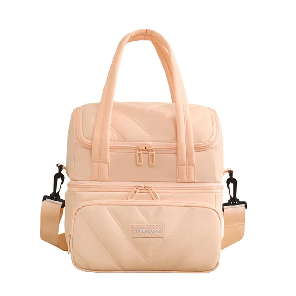 A light beige insulated reusable lunch bag with pink trim and carrying handles.