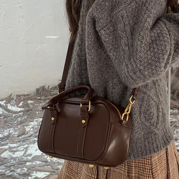 A brown vintage PU leather crossbody shoulder bag worn by a person, featuring a zippered closure and gold hardware.