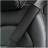 A close-up of a black PU leather embossed seat belt shoulder cushion on a dark car seat.