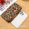 A leopard print retro long wallet lying next to a white smartphone on a wooden surface.