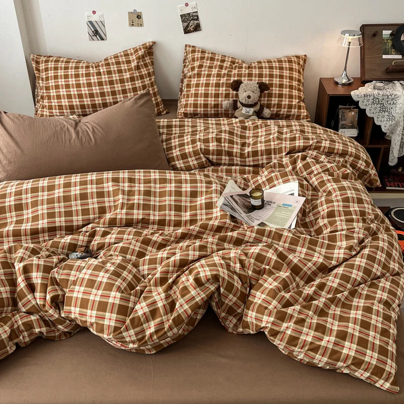A brown and tan plaid duvet cover set with matching pillows and a decorative throw blanket on a bed.