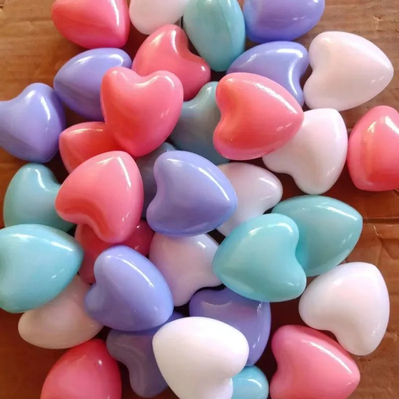 A pile of colorful, heart-shaped, non-toxic ball pit balls in shades of pink, purple, blue, and white.