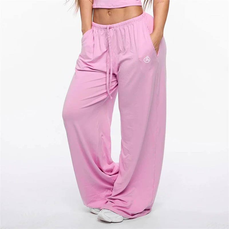 A woman is wearing light pink flare leggings with a high waist and drawstring detail.